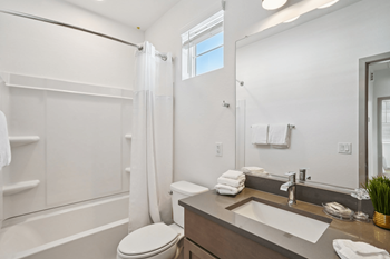 A white bathroom with a toilet, sink, and shower.
